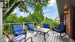 Spacious outdoor deck featuring gray wood-finish flooring, black iron railings, and mature surrounding greenery - 