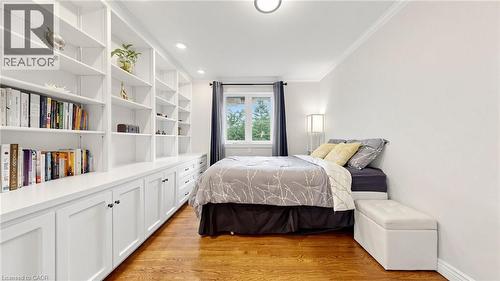 Built-in shelving and cabinetry along one wall, wood-finish flooring, recessed lighting, crown molding, and a window with dark curtains - 438 Lexington Road, Waterloo, ON 