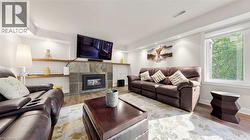 Living area featuring a fireplace with a slate surround, recessed lighting, wood-finish flooring, a large window, and built-in shelving - 