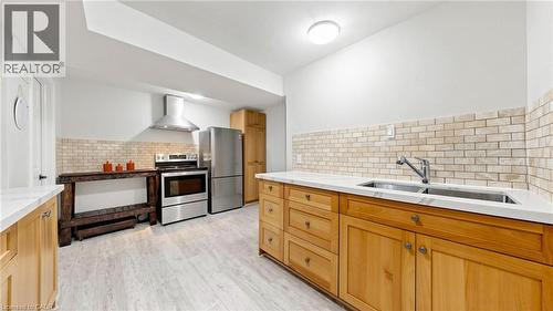 Kitchen featuring light wood cabinetry, white countertops, a subway tile backsplash, stainless steel appliances, and wood-finish flooring - 438 Lexington Road, Waterloo, ON 