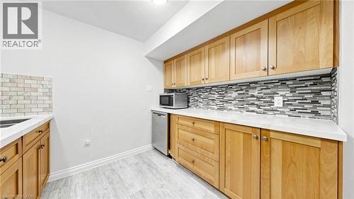 Compact kitchen space featuring light wood cabinetry with brushed nickel hardware, white countertops, and a full-height mosaic tile backsplash - 438 Lexington Road, Waterloo, ON 
