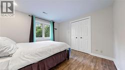Room featuring wood-finish flooring, a double window, and a white bi-fold closet door - 