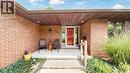 Brick exterior featuring a covered porch with concrete flooring, recessed lighting, and a prominent red front door - 438 Lexington Road, Waterloo, ON 
