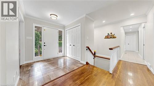 Inviting foyer featuring a white main entry door with sidelights, a built-in double-door closet, tiled flooring, and a hardwood staircase with white railings - 438 Lexington Road, Waterloo, ON 