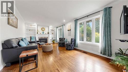 Living area featuring wood-finish flooring, a fireplace with a mantel, built-in shelving, triple-pane windows, and recessed lighting - 438 Lexington Road, Waterloo, ON 