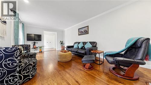 Spacious living area featuring polished wood-finish flooring, crisp white walls, and crown molding - 438 Lexington Road, Waterloo, ON 