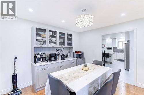 Dining area featuring a coffee bar with upper glass-front cabinetry, a crystal chandelier, recessed lighting, and wood-finish flooring - 214 Merrilee Crescent, Hamilton, ON 