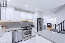 Well-appointed kitchen featuring white cabinetry, light gray countertops, and stainless steel appliances - 
