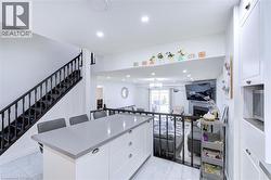 Modern kitchen island featuring a light-toned countertop, white cabinetry with hardware, and seating for three - 