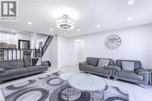 Open-concept living area featuring light-colored tile flooring, white walls, and recessed lighting - 214 Merrilee Crescent, Hamilton, ON 
