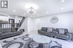 Open-concept living area featuring light-colored tile flooring, white walls, and recessed lighting - 