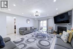 Living room featuring recessed ceiling lighting, a contemporary chandelier, a brick fireplace, and sliding glass doors opening to the backyard - 