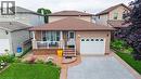 Brick exterior featuring a covered front porch with white railing, a single-car garage, and a concrete driveway with a decorative border - 214 Merrilee Crescent, Hamilton, ON 