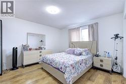 Bedroom with wood-finish flooring, a window with curtains, and a ceiling-mounted light fixture - 