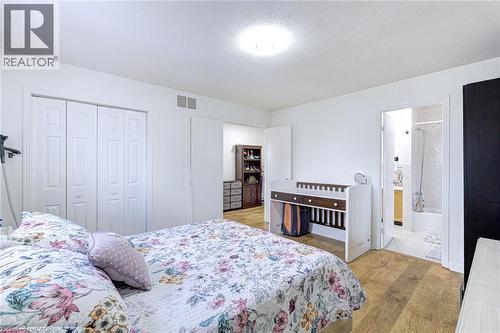 Bedroom with wood-finish flooring, white walls, and a ceiling light fixture - 214 Merrilee Crescent, Hamilton, ON 