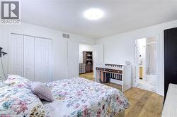 Bedroom with wood-finish flooring, white walls, and a ceiling light fixture - 