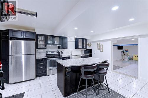 Modern kitchen featuring dark cabinetry, stainless steel appliances, a center island with bar seating, and recessed lighting - 214 Merrilee Crescent, Hamilton, ON 