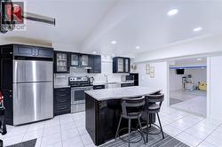 Modern kitchen featuring dark cabinetry, stainless steel appliances, a center island with bar seating, and recessed lighting - 