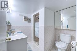 Bathroom featuring a vanity with an integrated sink, a glass-enclosed shower, a wall-mounted medicine cabinet, and light-toned floor and wall tiling - 