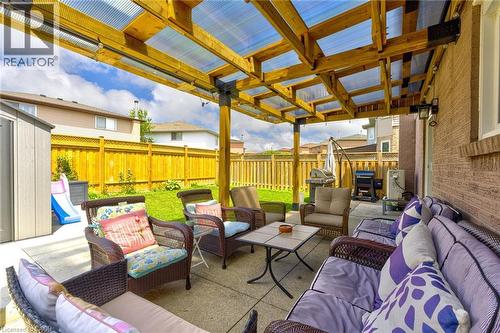 Paved patio area featuring a clear corrugated roof, wooden pergola structure, and brick exterior wall - 214 Merrilee Crescent, Hamilton, ON 