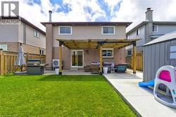 Rear exterior featuring a brick and siding facade, a ground-level concrete patio with a wood pergola, a sliding glass door, and a green lawn area - 