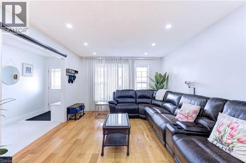 Open-concept living area featuring wood-finish flooring, recessed lighting, and large windows with vertical blinds - 214 Merrilee Crescent, Hamilton, ON 