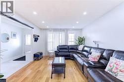 Open-concept living area featuring wood-finish flooring, recessed lighting, and large windows with vertical blinds - 