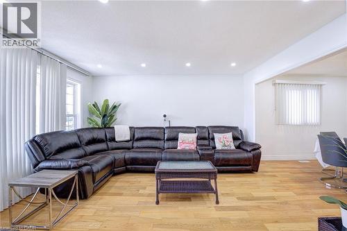 Open-concept living area featuring light wood-finish flooring, recessed ceiling lighting, and crisp white walls - 214 Merrilee Crescent, Hamilton, ON 