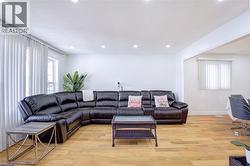 Open-concept living area featuring light wood-finish flooring, recessed ceiling lighting, and crisp white walls - 