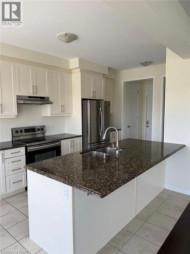 Kitchen featuring white cabinetry, dark granite countertops, stainless steel appliances, and a central island with an integrated sink - 63 Ridge Road Unit# Upper, Cambridge, ON 