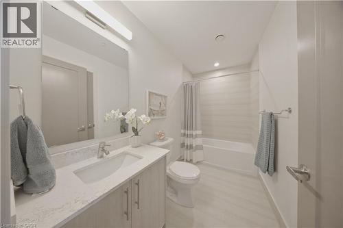 Bathroom featuring a vanity with an integrated sink and light-toned countertop, brushed nickel faucet, full-width mirror, and overhead linear lighting - 1055 Weber Street E Unit# 207, Kitchener, ON 