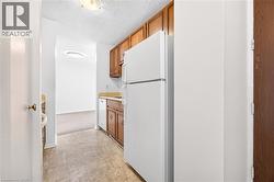 Galley kitchen featuring wood cabinetry, white appliances, and vinyl flooring - 