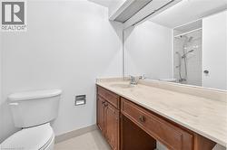 Bathroom featuring a wood-finish vanity with a light-toned countertop, an integrated sink, and a large wall-mounted mirror - 