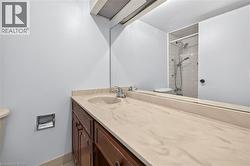 Bathroom vanity featuring an integrated sink with a single-handle faucet, a full-width mirror, and a wood-finish cabinet with storage - 