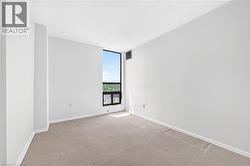 Floor-to-ceiling window offering outdoor scenery, neutral wall tones, textured carpeting, and white baseboards - 