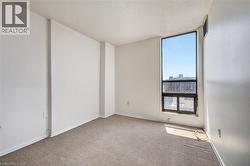 Spacious room featuring a large full-height window, broad baseboards, and neutral wall paint - 