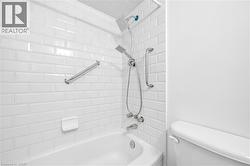 Bathtub with white subway tile surround, chrome fixtures, and a dual-head shower system - 