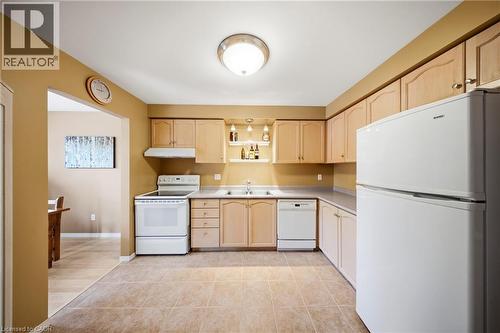 Kitchen featuring light wood-finish cabinetry, white appliances, and tiled flooring - 16 Scottacres Boulevard, Caledonia, ON 