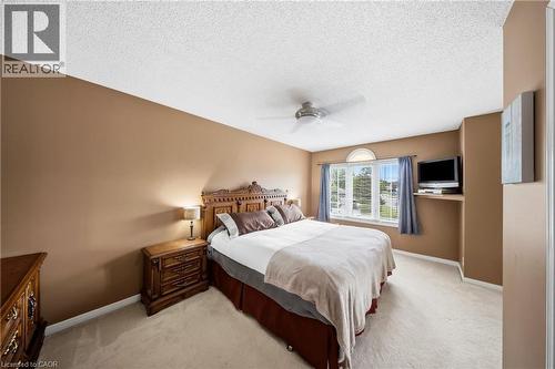 Carpeted room featuring a large window with an arched transom, a ceiling fan, and a built-in wall shelf - 16 Scottacres Boulevard, Caledonia, ON 