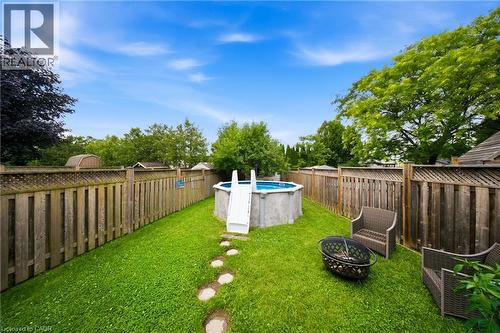 Expansive backyard featuring a lush lawn, an above-ground pool with ladder, and a stone paver pathway - 16 Scottacres Boulevard, Caledonia, ON 