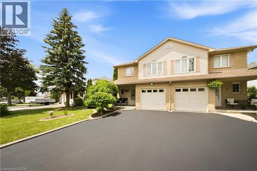 Two-story residence featuring a brick and siding facade, arched window above the entry, double garage, and a paved driveway - 16 Scottacres Boulevard, Caledonia, ON 