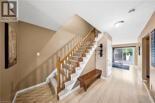 Foyer featuring light wood-finish flooring, staircase with carpeted treads and wood railing, and neutral wall tones - 16 Scottacres Boulevard, Caledonia, ON - Indoor Photo Showing Other Room