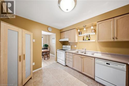 Kitchen featuring light wood-finish cabinetry, a dual basin stainless steel sink, and white appliances including a range and dishwasher - 16 Scottacres Boulevard, Caledonia, ON 