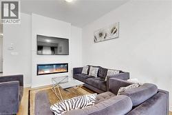 Living area featuring an integrated linear fireplace, hardwood-finish flooring, and crisp white walls - 