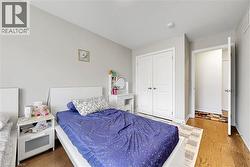 Bedroom featuring light-toned walls, wood-finish flooring, a white bi-fold closet, and a white interior door - 