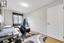 Interior room featuring light wood-finish flooring, a contemporary white two-panel door with brushed nickel hardware, and a window with dark sheer curtains - 