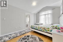 Hardwood flooring extends throughout this space, complemented by a large window with white sheer curtains - 