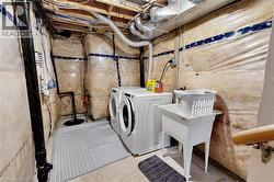 Basement utility area featuring exposed joists, insulation, and concrete flooring - 