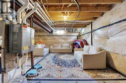 Unfinished basement featuring exposed ceiling joists, visible insulation, and a tankless water heater installation - 
