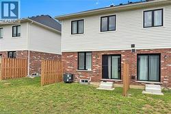 Rear exterior featuring brick and siding construction, multiple sliding glass patio doors, and a wood privacy fence - 